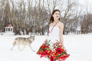 Adolescente dans une robe d'été fleurie dans un paysage de neige avec une forêt et un loup en arrière-plan.