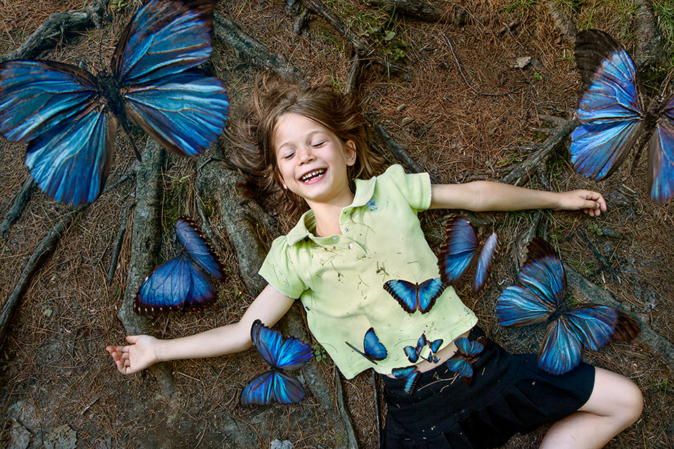 Photo montage d'une enfant qui rit avec des papillons qui sortent de son ventre