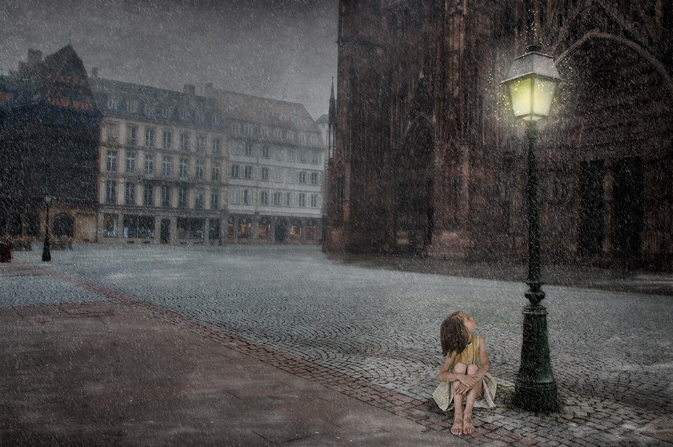 Photo montage of a child sitting under a lamp-post with snow falling