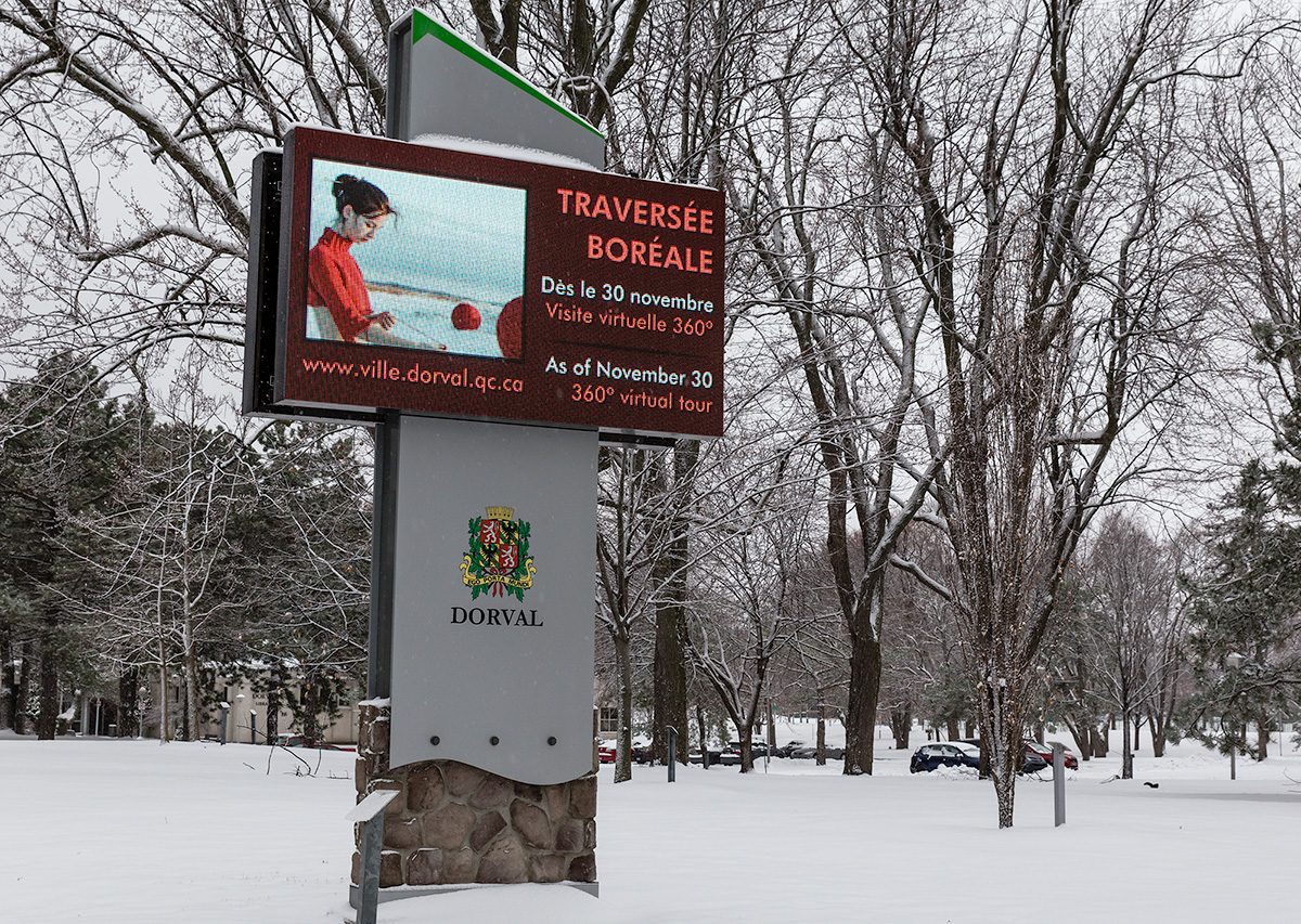 Illuminated sign in a park announcing the photo exhibit Traversée boréale in Dorval