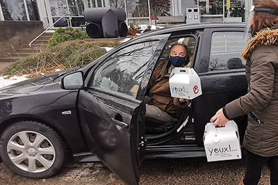 trio-plein-les-yeux-cne-art-a-emporter-jonquiere Photo d'un homme qui ouvre la portière d'une auto en tenant une boîte trio culturel du CNE