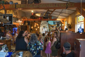 Intérieur d'un resto-brasserie bondé de monde. Sur la poutre du plafond on peut lire : LES BIÈRES DE LA NOUVELLE FRANCE.